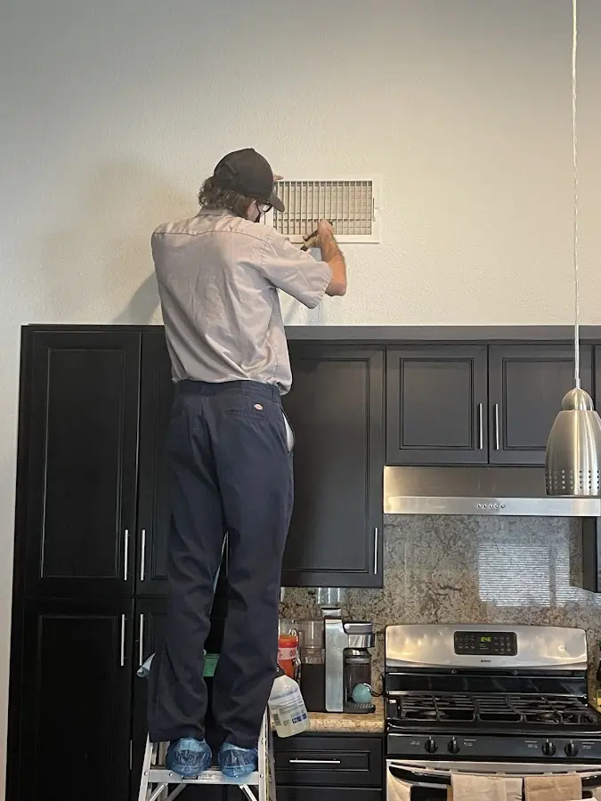 Technician inspecting an air vent during HVAC service in Pimmit Hills